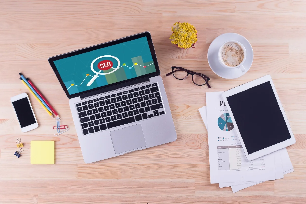 E-E-A-T in SEO: Unraveling the Secret Sauce of Online Success 6 A laptop on a wooden table with a magnifying glass, optimized for SEO.