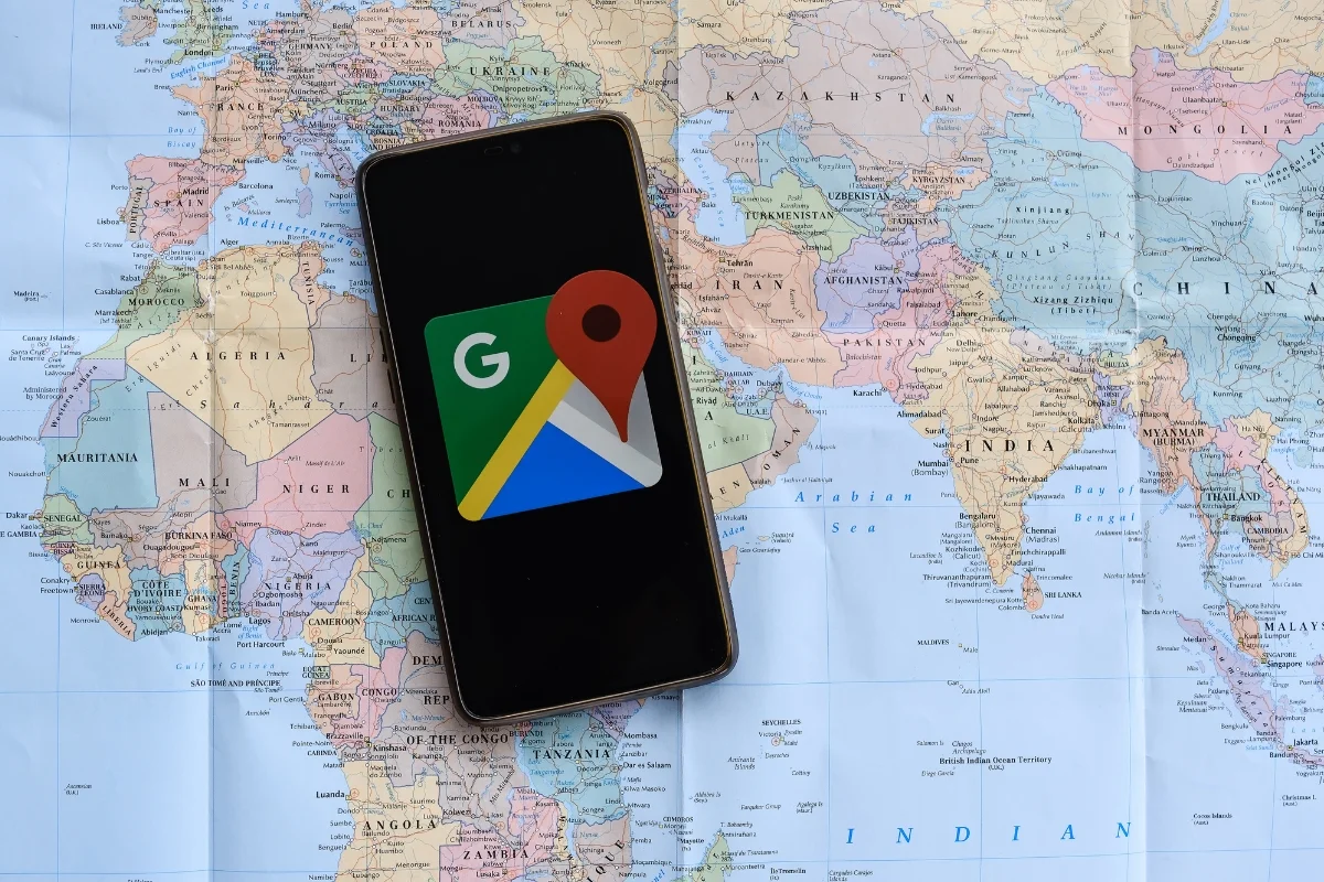 Smartphone with Google Maps and Google 3 Pack app on a world map background.
