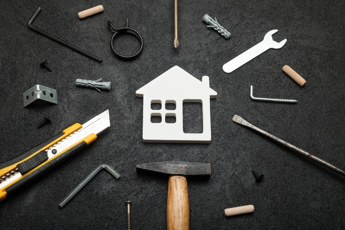 Home Service Companies & Local SEO: Improve Local Visibility 3 Assorted DIY tools and a house-shaped cutout from home service companies arranged on a dark surface.
