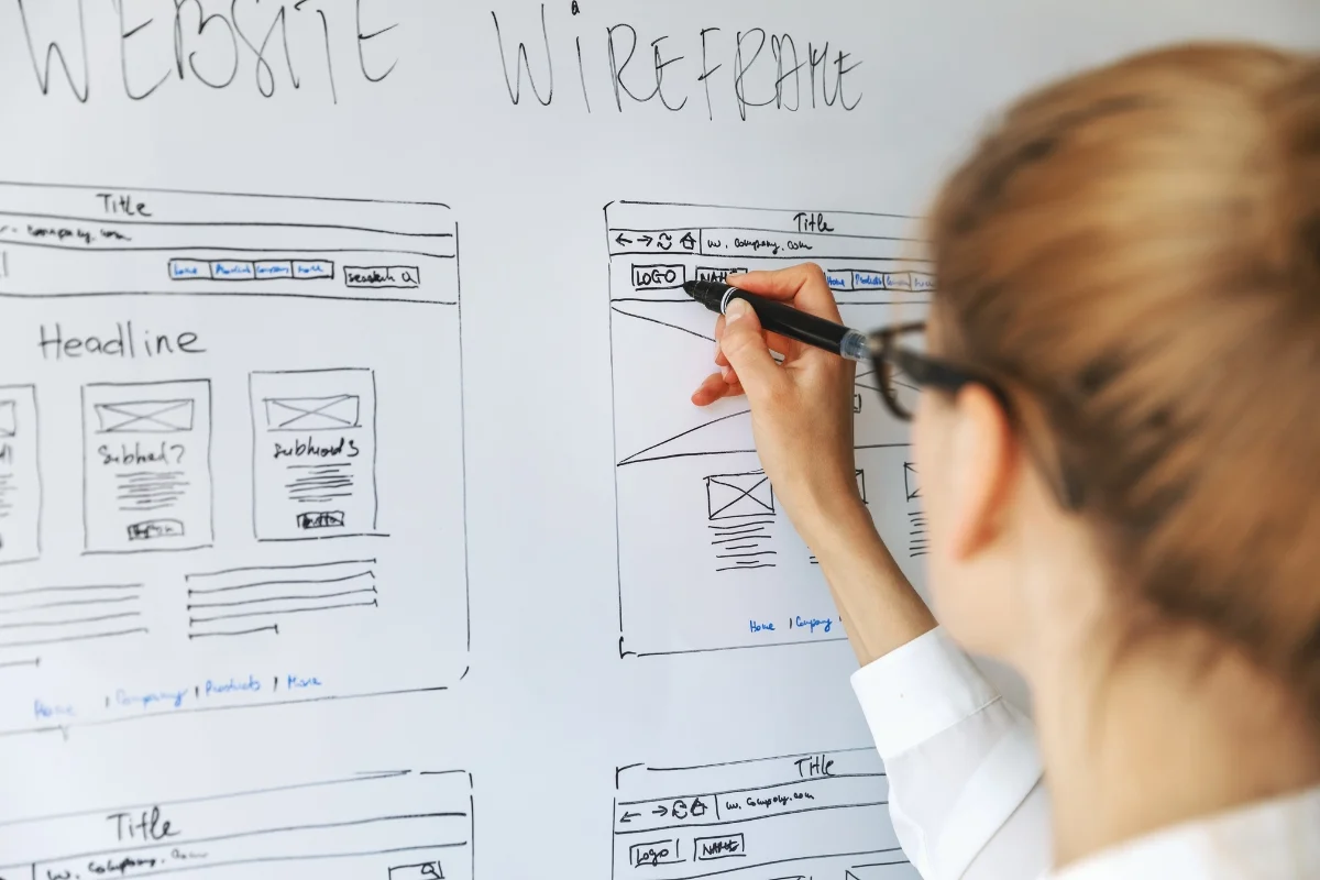 How to Create Wireframes: A Beginner's Guide for Stunning Designs 6 A person illustrating how to create website wireframes on a whiteboard.