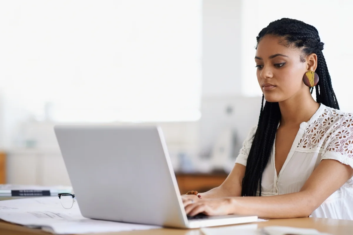 How to Search on a Website: Mastering the Art of Navigation 7 A focused young woman with braided hair learning how to search on a website using a laptop at a desk in a brightly lit office.