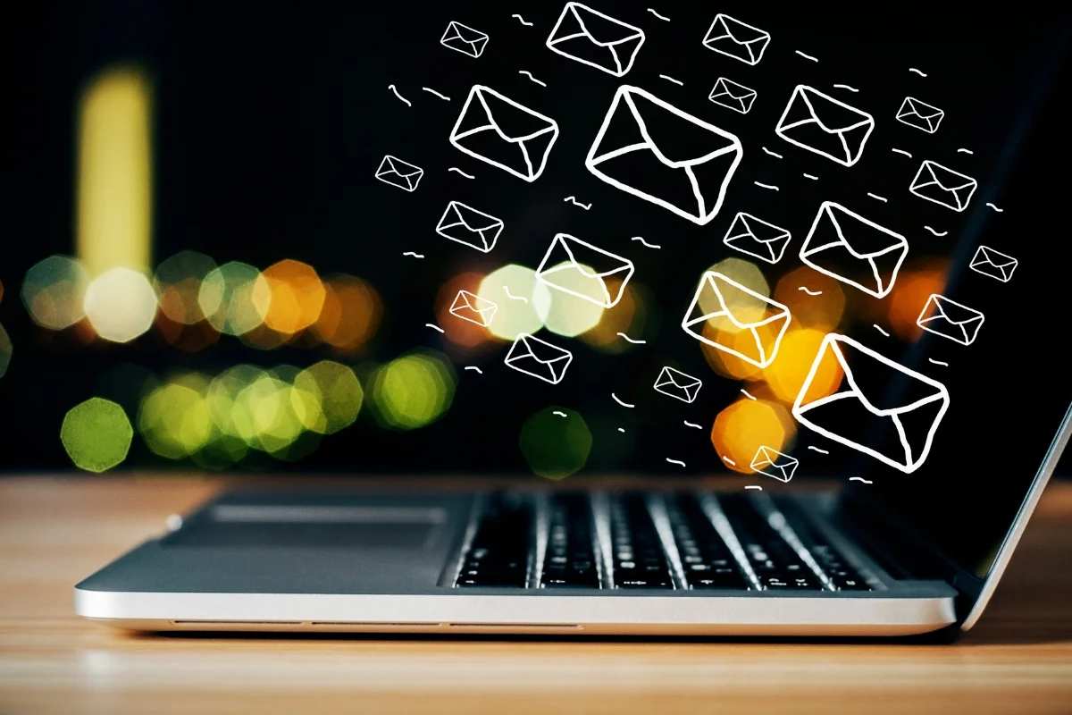 Email Marketing for Plumbers: Boost Your Plumbing Business Effectively 4 A laptop with numerous email icons floating above the keyboard, set against a blurred city lights background, illustrates the power of email marketing for plumbers.