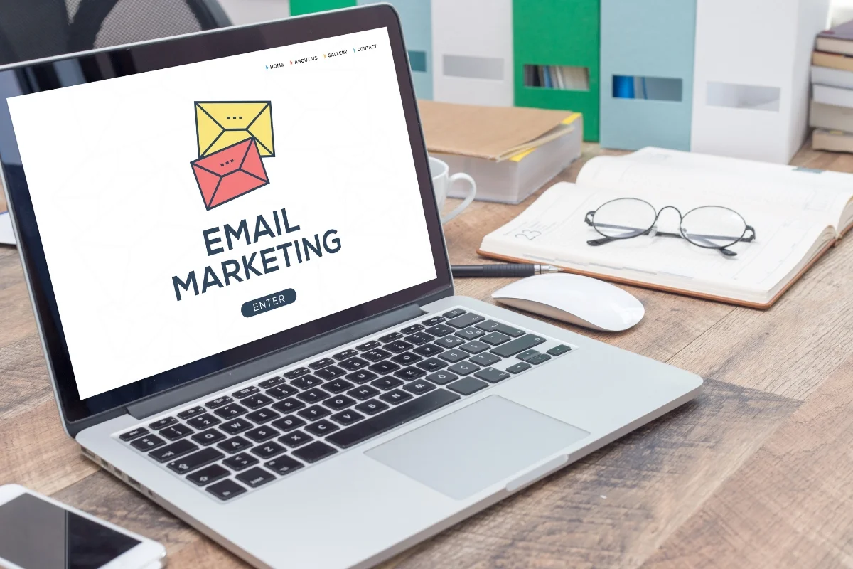 Email Marketing for Plumbers: Boost Your Plumbing Business Effectively 6 A laptop displaying an email marketing page for plumbers on its screen. The table also holds a notebook, glasses, and a cup of coffee.
