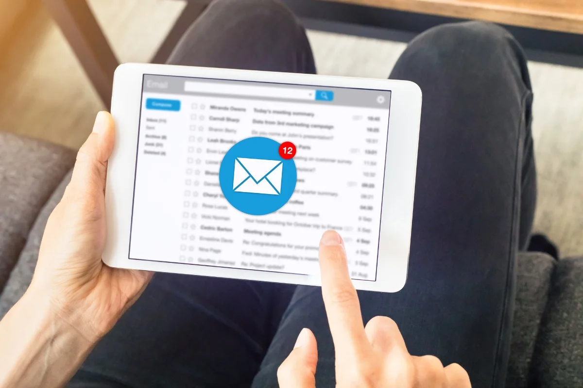 Email Targeting: Master the Art of Personalized Messaging 6 A person using a tablet to check emails, showing 12 new messages with email targeting techniques in play.