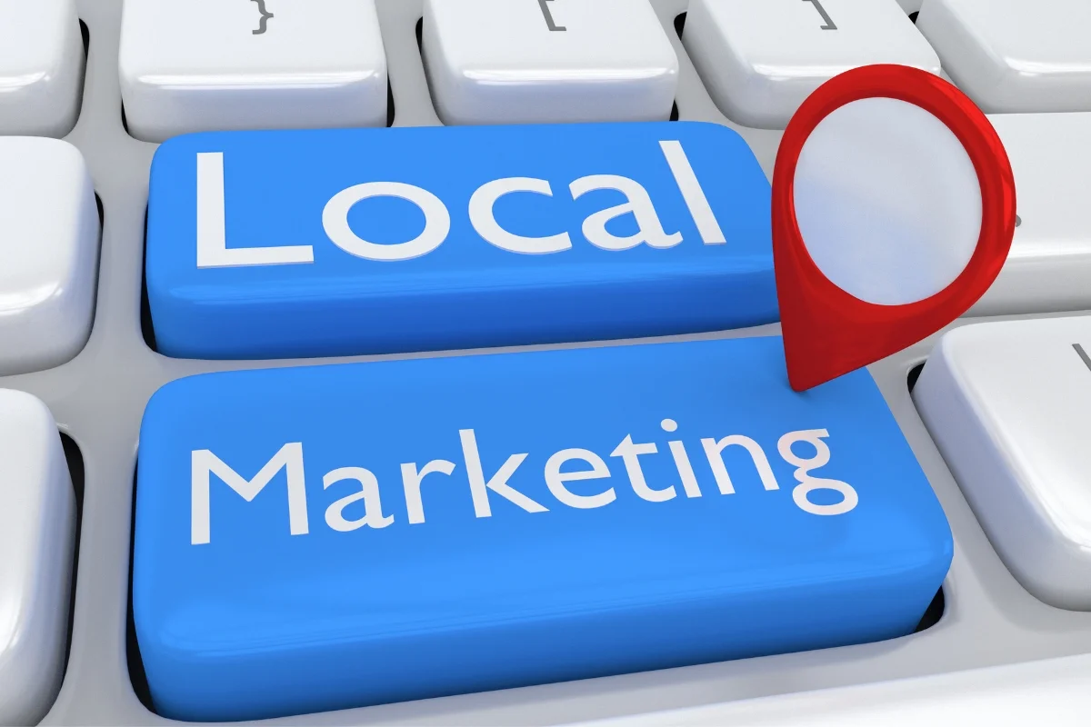 What Is Hyperlocal Marketing: Targeting for Local Business Growth 3 Close-up of a keyboard with two blue keys labeled "Local" and "Marketing" in white text. A red map pin icon is placed over the keys, hinting at the concept of "What Is Hyperlocal Marketing.