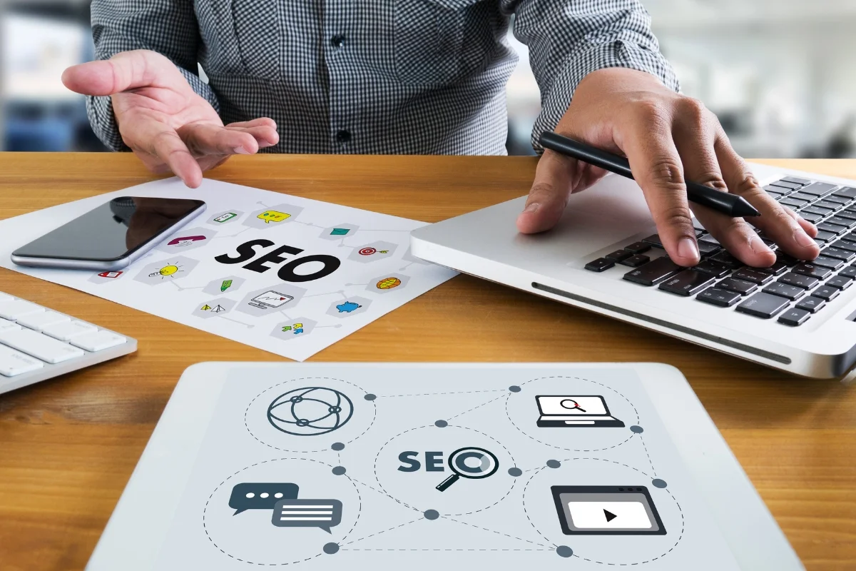 What Is Hyperlocal Marketing: Targeting for Local Business Growth 6 A person working on an SEO strategy with a laptop, tablet, smartphone, and printed materials on a wooden desk dives into understanding what is hyperlocal marketing.