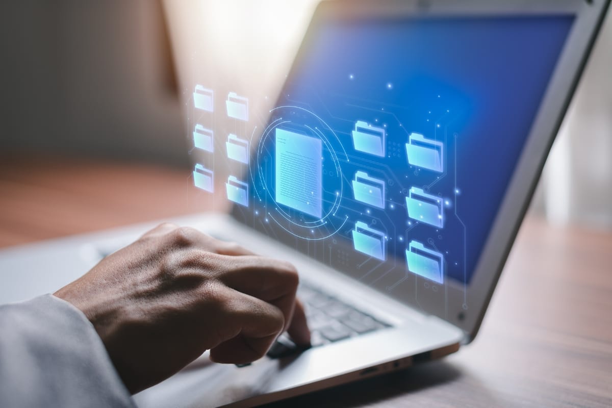 Must-Have Database Maintenance Plugins for WordPress 10 A hand touches the laptop touchpad, with digital icons of folders and a document floating above the screen, seamlessly symbolizing database maintenance and efficient digital data management.