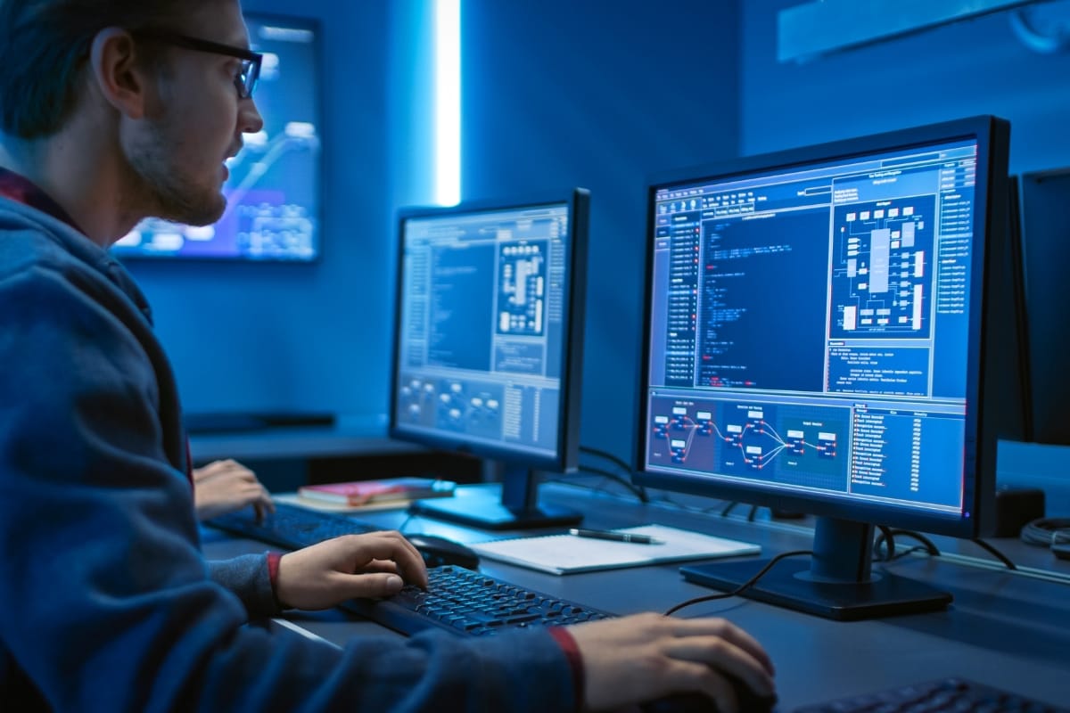 Must-Have Database Maintenance Plugins for WordPress 8 In a dimly lit room, a person is engrossed in database maintenance, working on multiple computer screens displaying intricate code and data.