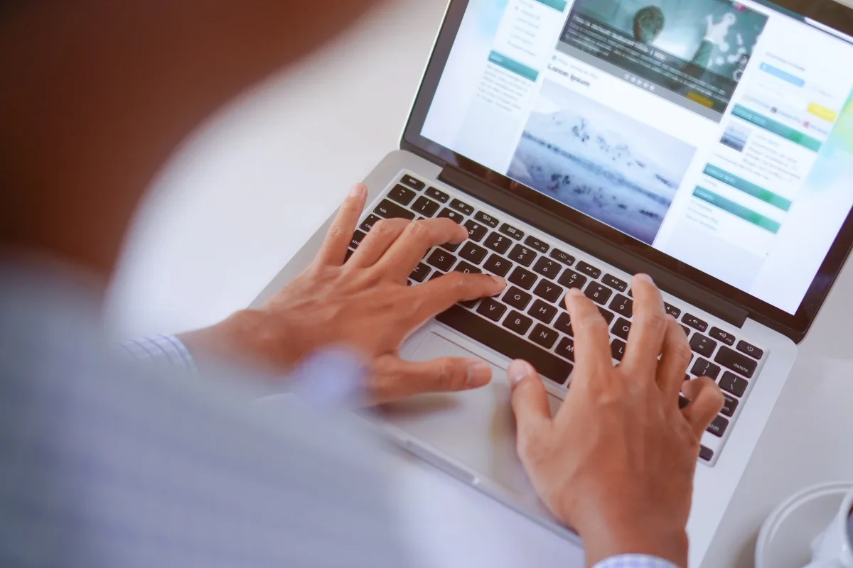 Enhance Your WordPress Site by Mastering Engaging Content Creation 2 A person is typing on a laptop, fully immersed in engaging content creation, while viewing a webpage brimming with dynamic text and captivating images.