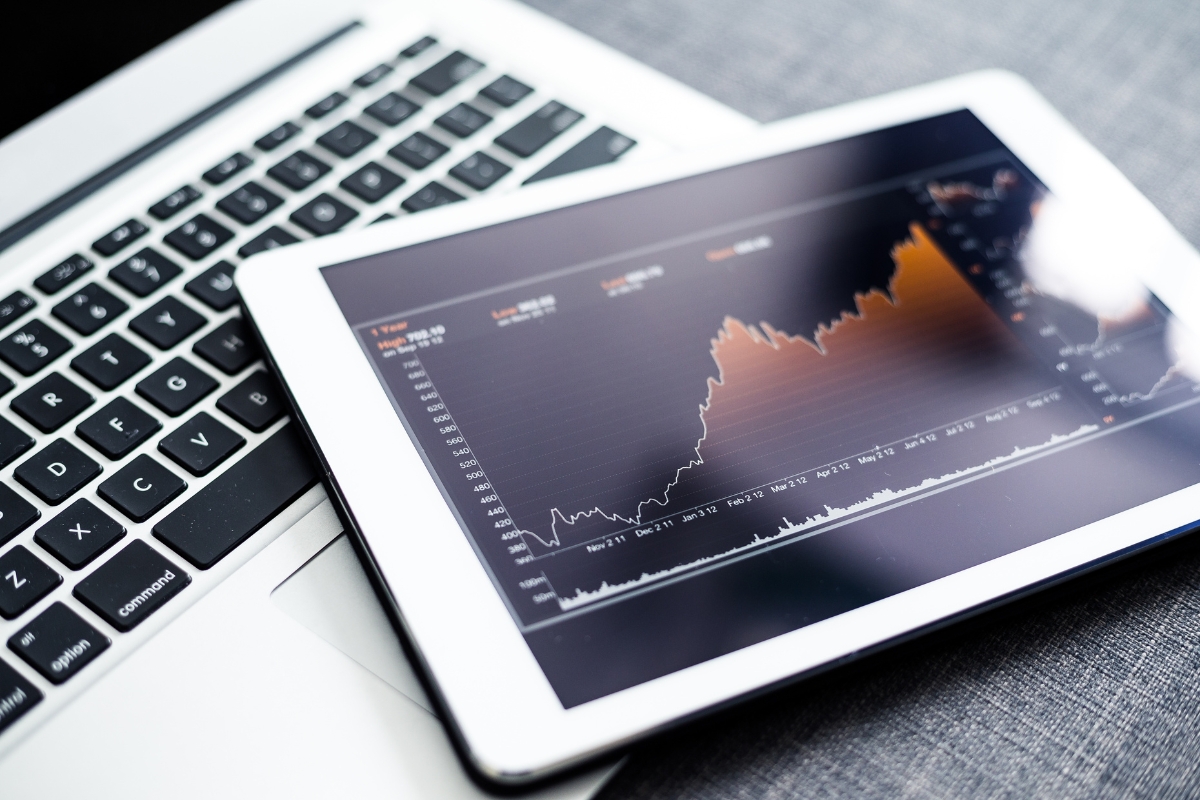 Blockchain in Digital Marketing: Potential Use Cases 7 A tablet displaying a line graph with rising and falling data trends rests on top of a laptop keyboard, illustrating the impact of blockchain in digital marketing analytics.