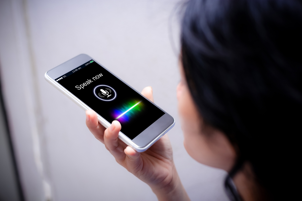 How Does Voice Search Work? A Beginner’s Guide to Smart Technology 4 A person holds a smartphone with a voice assistant app open, displaying a microphone icon and the words “Speak now,” visually illustrating how voice search works.