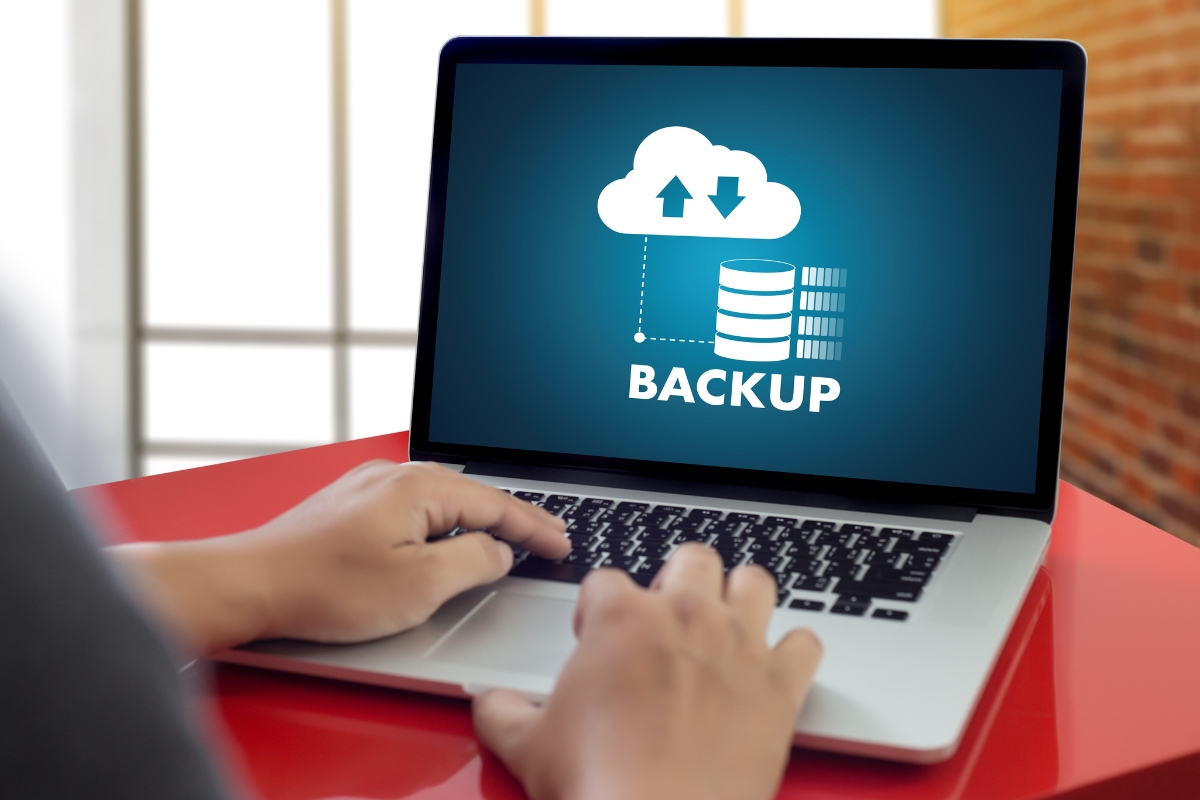 Person using a laptop displaying a backup icon with a cloud and database, highlighting seamless data transfer to the cloud—ideal for managing backups with must-have plugins.