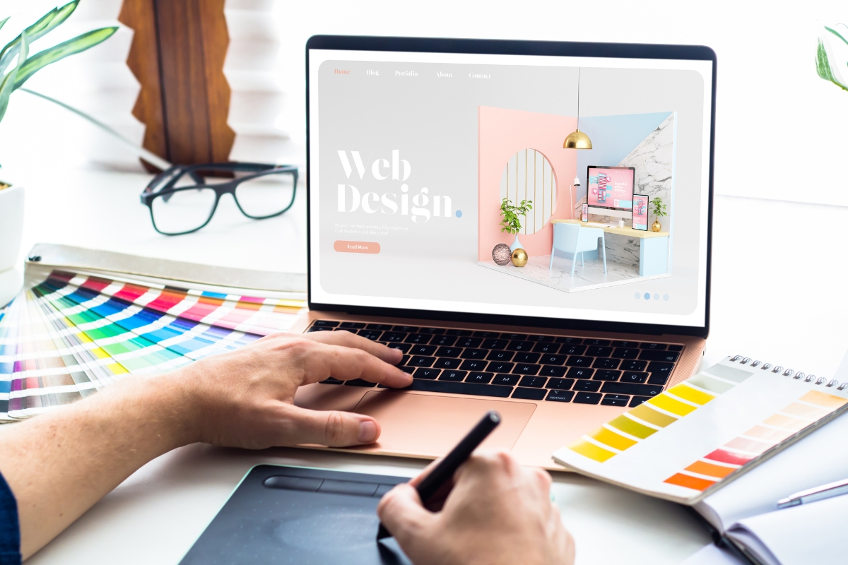 Web Accessibility: Designing for All Users 4 A person uses a stylus and laptop displaying a web design interface focused on Web Accessibility, with color swatches and a tablet on the desk.