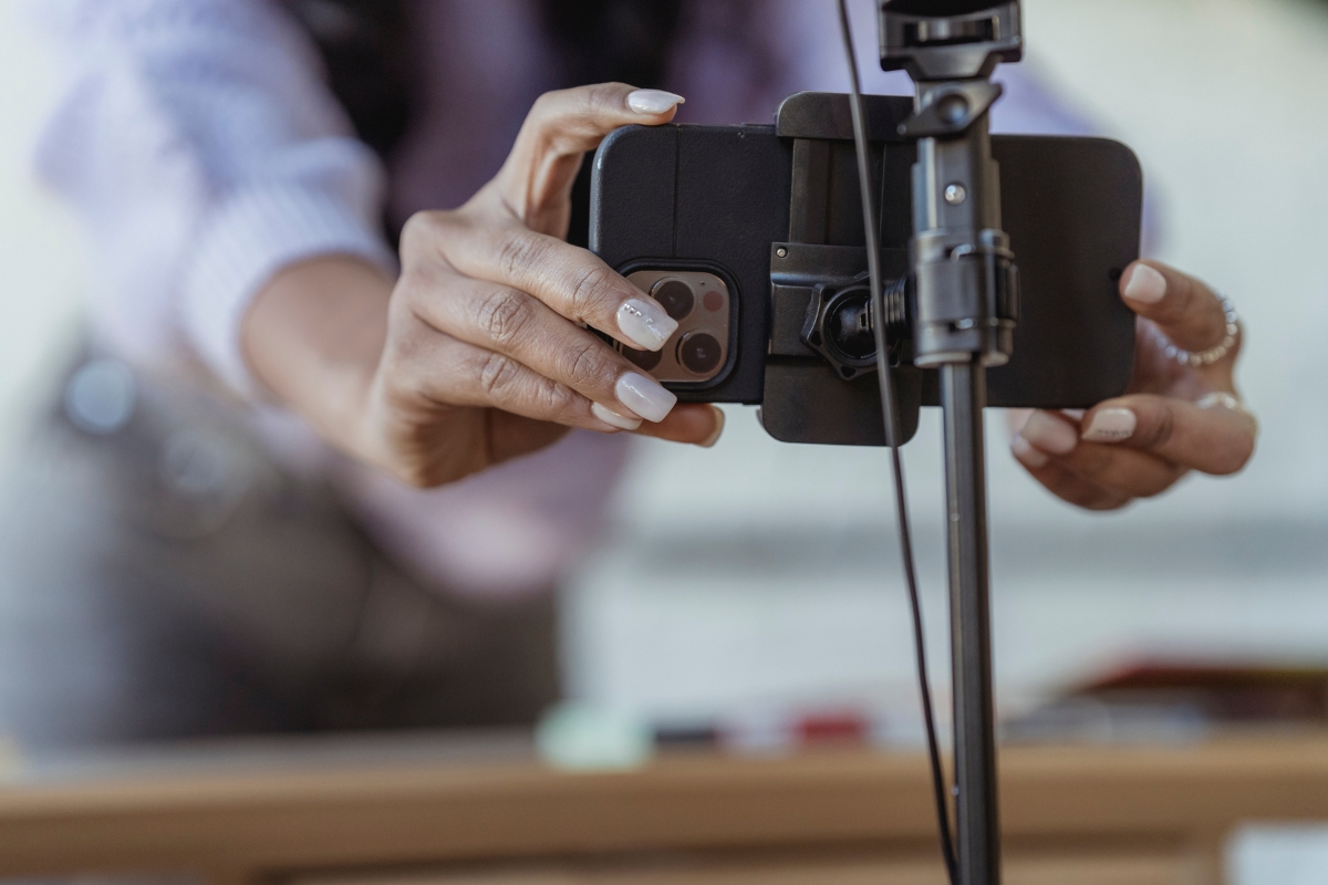 Live Streaming: Engaging Your Audience in Real-Time 2 A person adjusts a smartphone mounted on a tripod, preparing it for live streaming or capturing a photo.