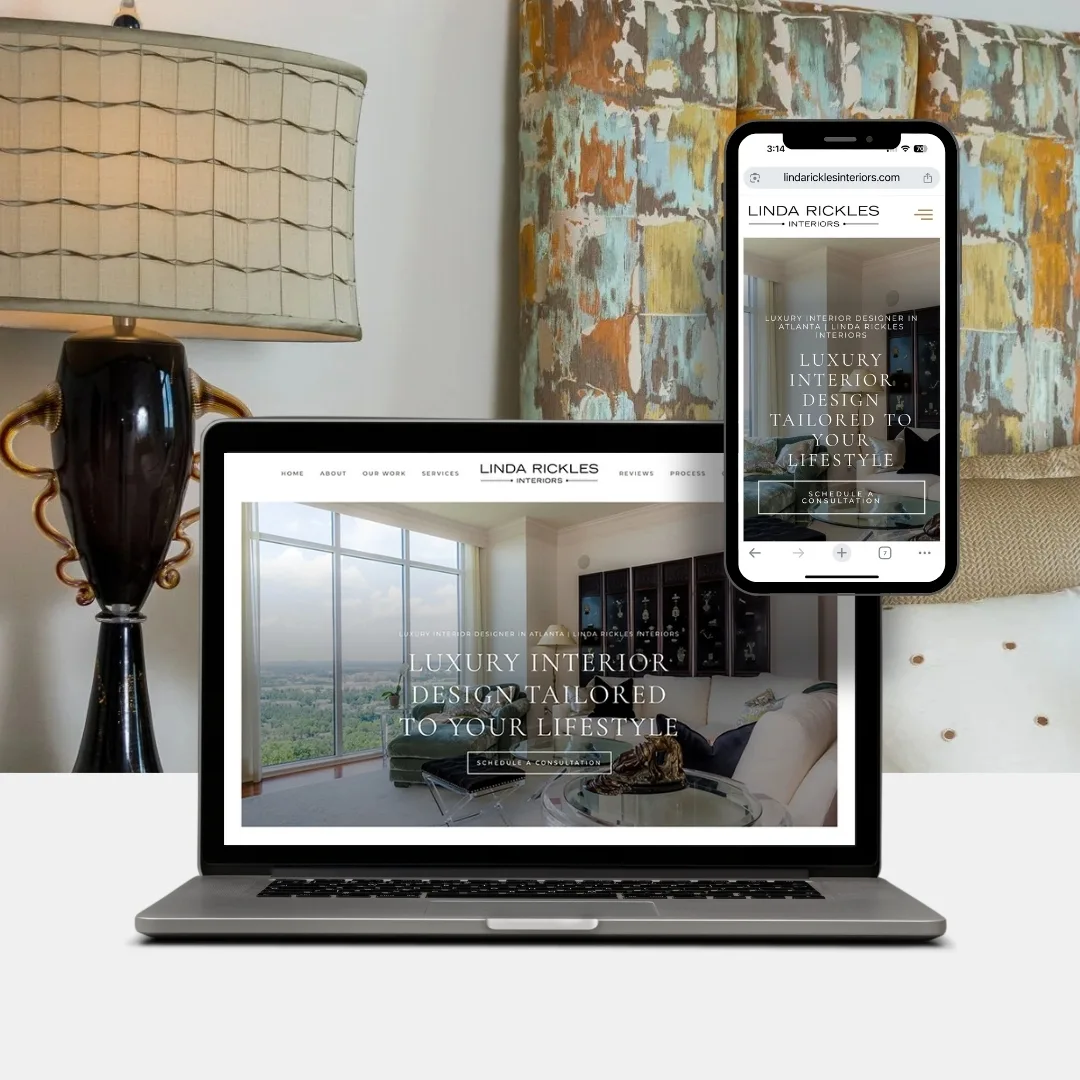A laptop and smartphone display the Linda Rickles Interiors website, set on a desk with a lamp and decorative art in the background, showcasing the elegant design style of Linda Rickles Interiors.